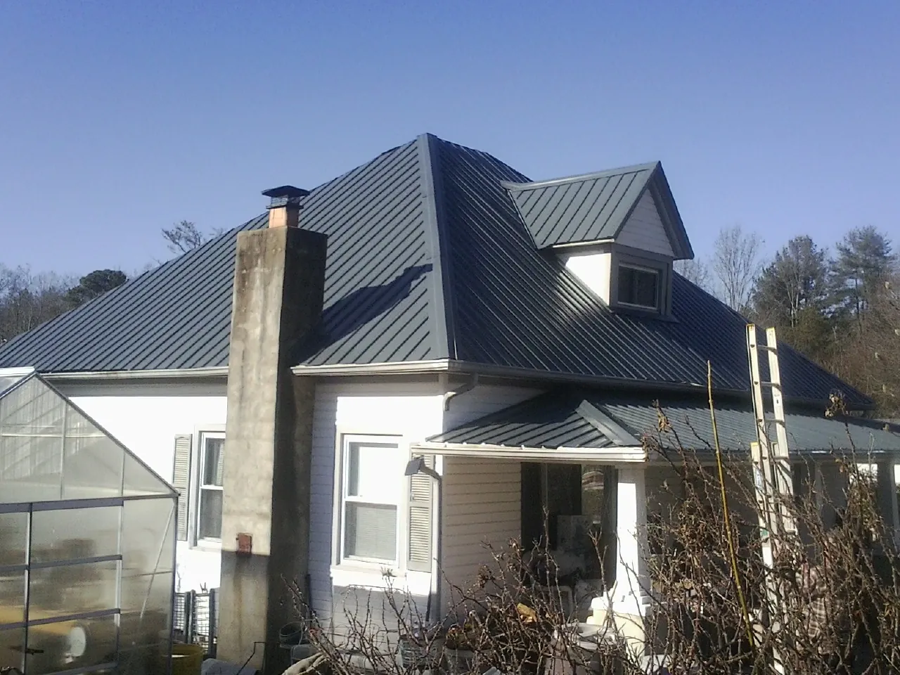 Dark blue standing seam metal roof on a white farmhouse with dormer — Slate & Tile Roof Repair by Roofing Brothers in Mooreton