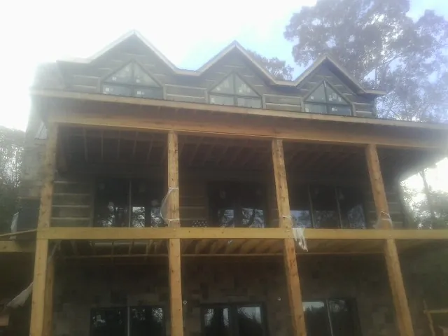 Dormers and porch framing on a large log home under construction — Roof Coating work by our crew in Mooreton