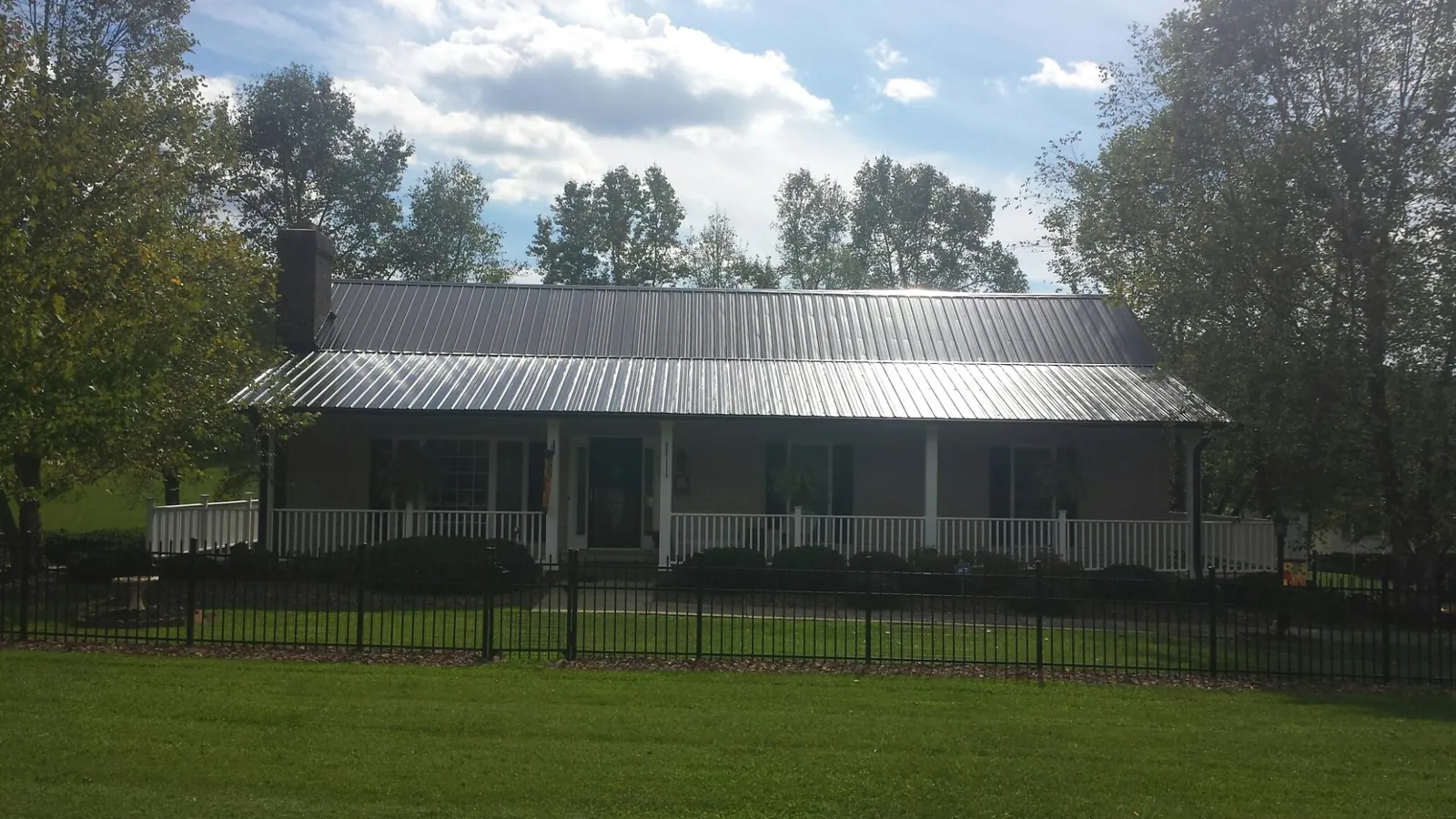 Gray metal roof on a brick ranch with a full width front porch — Gutter Guard Installation work by our crew in Mooreton