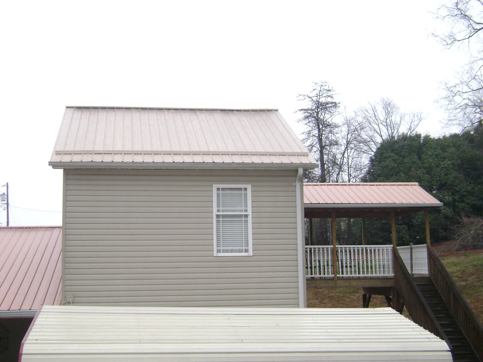 Tan metal roofs on a two story addition and attached porch, from a Roof Replacement job in Mooreton